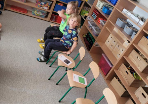 Dzieci mają za zadanie usiąść na krzesełkach z usłyszaną nazwą koloru.