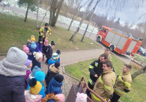 Dzieci stoją ze strażakami, czekają na rozpoczęcie prelekcji