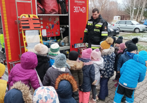 Dzieci oglądają pompę do wody i tył samochodu strażackiego
