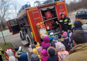 Dzieci oglądają pompę do wody i tył samochodu strażackiego