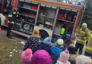 Dzieci oglądają i słuchają co znajduje się we wnętrzu wozu strażackiego