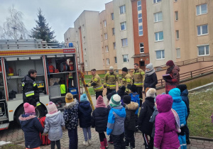 Dzieci stoją przed wozem strażackim - czekają na rozpoczęcie prelekcji