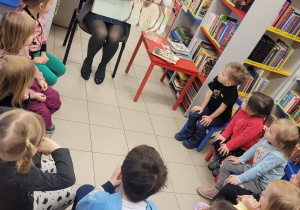 Dzieci słuchają Pani bibliotekarki jak czyta książkę o Łosiu Erneście