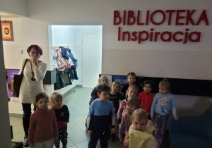 Dzieci stoją pod napisem z nazwą biblioteki