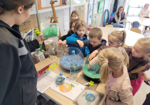 Dzieci stoi przed stołem z przetworzonymi ze śmieci produktami, sprawdzają dotykiem
