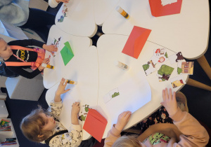 Dzieci przy stolikach układają obrazek pocięty na części