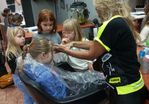 Dziewczynki podglądają jak pani fryzjerka wykonuje fryzurę na głowie Jagódki