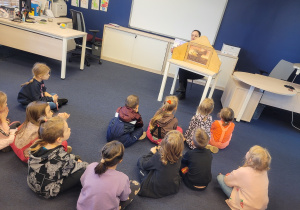 Dzieci słuchają i oglądają bajkę Smok Wawelski za pomocą teatrzyki KAMISHIBA