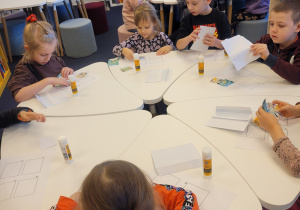 Dzieci przy stolikach układają historyjkę obrazkową o smoku wawelskim