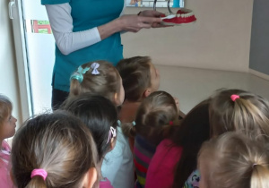 Dzieci stoją a pani Stomatolog pokazuje sprzęt dentystyczny