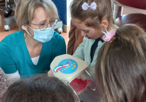 Melisa przy pomocy Pani Stomatolog myje zęby na specjalnej dentystycznej jamie ustnej
