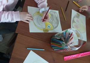 Dziewczynka maluje portret małpki kredkami