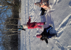 Dziewczynki robią aniołki na śniegu