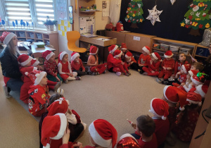 Dzieci siedzą w kole na dywanie słuchają opowieści o Mikołaju