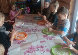 Dzieci siedzą przy stole formuują chlebki