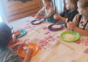 Dzieci siedzą przy stole formuują chlebki