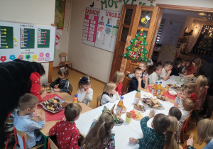 Dzieci siedzą przy zastawionymi stołami