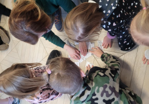 Dzieci wraz z pomocą Pani Oli układają puzzle z papieru