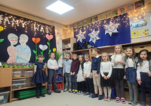 Dzieci recytują wierszyk stojąc pod dekoracją