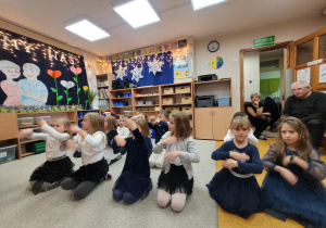 Dzieci tańczą - fragment tańca- siedzą na dywanie