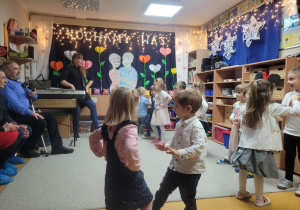 Dzieci tańczą trzymając ręce na biodrach i noga w górze