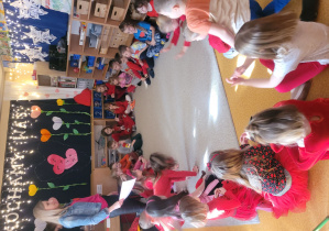 Dzieci siedzą na dywanie w kole ubrani na czerwono