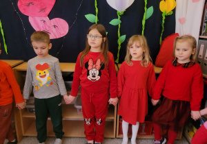 Dziewczynki stoją trzymają się za ręce ubrani są na czerwono