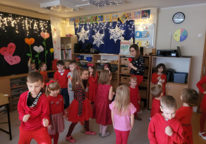 Dzieci tańczą na dywanie ubrani są na czerwono