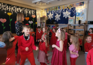 Dzieci tańczą na dywanie ubrani są na czerwono