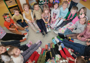 Dzieci z nogami do środka koła prezentują swoje kolorowe skarpetki