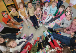 Dzieci z nogami do środka koła prezentują swoje kolorowe skarpetki