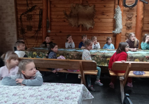 Dzieci siedzą przy długich stołach