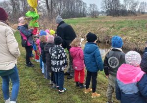 Dzieci stoją na brzegu rzeki, czekają na utopienie Marzanny