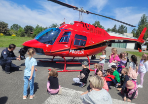 Dzieci ogladają czerwony helikopter policyjny