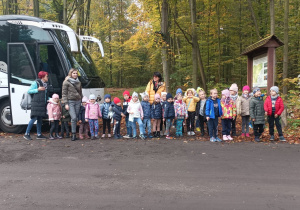 Całe przedszkole stoją przed autokarem pozują do zdjęcia.