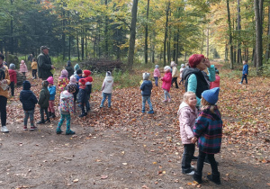 Dzieci biegają po leśnym terenie.