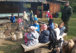 Dzieci siedzą przy ognisku.