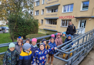 Dzieci pozują do zdjęcia przed wejsciem do biblioteki