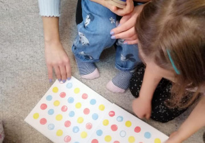 Dzieci oglądają książkę na dywanie.