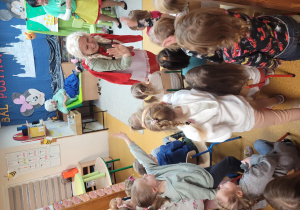 Czerwony Kapturek przybija piątki z dziećmi, które siedzą na widowni.