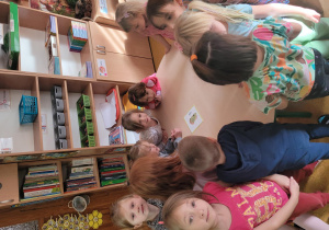 Dzieci stoją przy stoliku gdzie leży obrazek kiwi