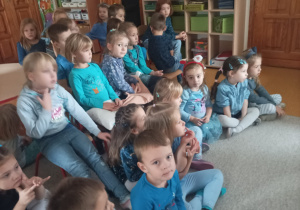Dzieci siedzą na krzesełkach i oglądają film edukacyjny o prawach dziecka
