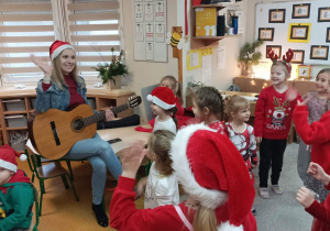 Pani Paulina graja na gitarze, dzieci szaleją na dywanie