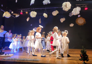 Dzieci krążą po kole na scenie - prezentują stroje aniołków