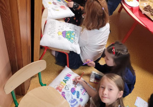 Dziewczynki już malują poduszkę, którą otrzymały w prezencie