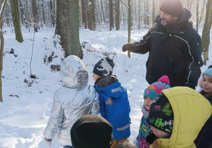 Dzieci ogladają co wokół nich przynosi las. Przewodnik im tłumaczy