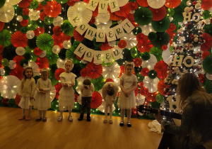 Dzieci kłaniają się po występie, niektóre stoją na tle dekoracji