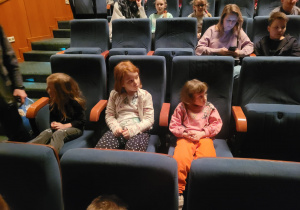 Dzieci siedzą na widowni i czekają na spektakl