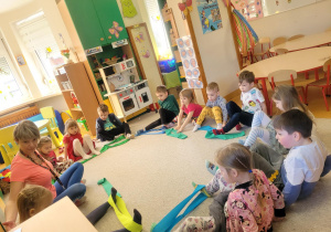 Dzieci siedzą z szarfami na dywanie